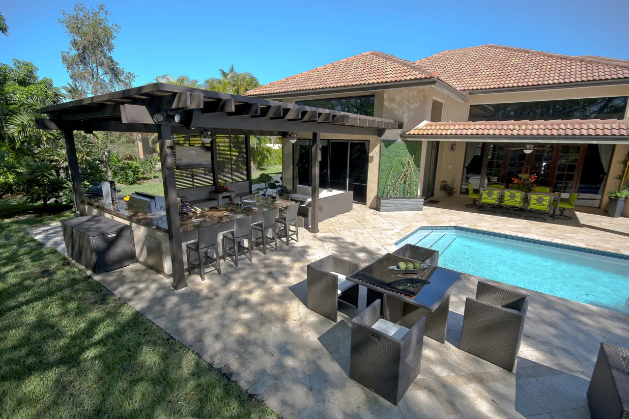Dark pergola over an outdoor kitchen and bar beside a screened pool in Tampa